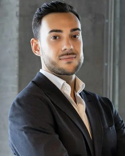 Original photo: a young man in a dark suit with his arms crossed
