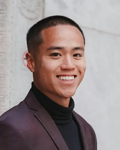 Original photo: a young man in a dark red suit by a stone wall