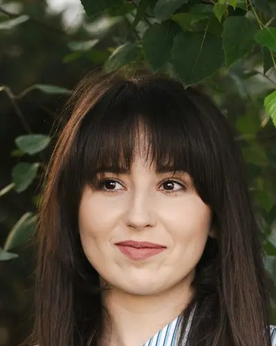 Original photo: a young woman with bangs in a striped shirt near trees